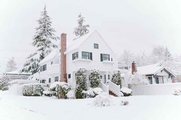 Charming white house surrounded by snow, offering a perfect winter retreat and an ideal property for sale