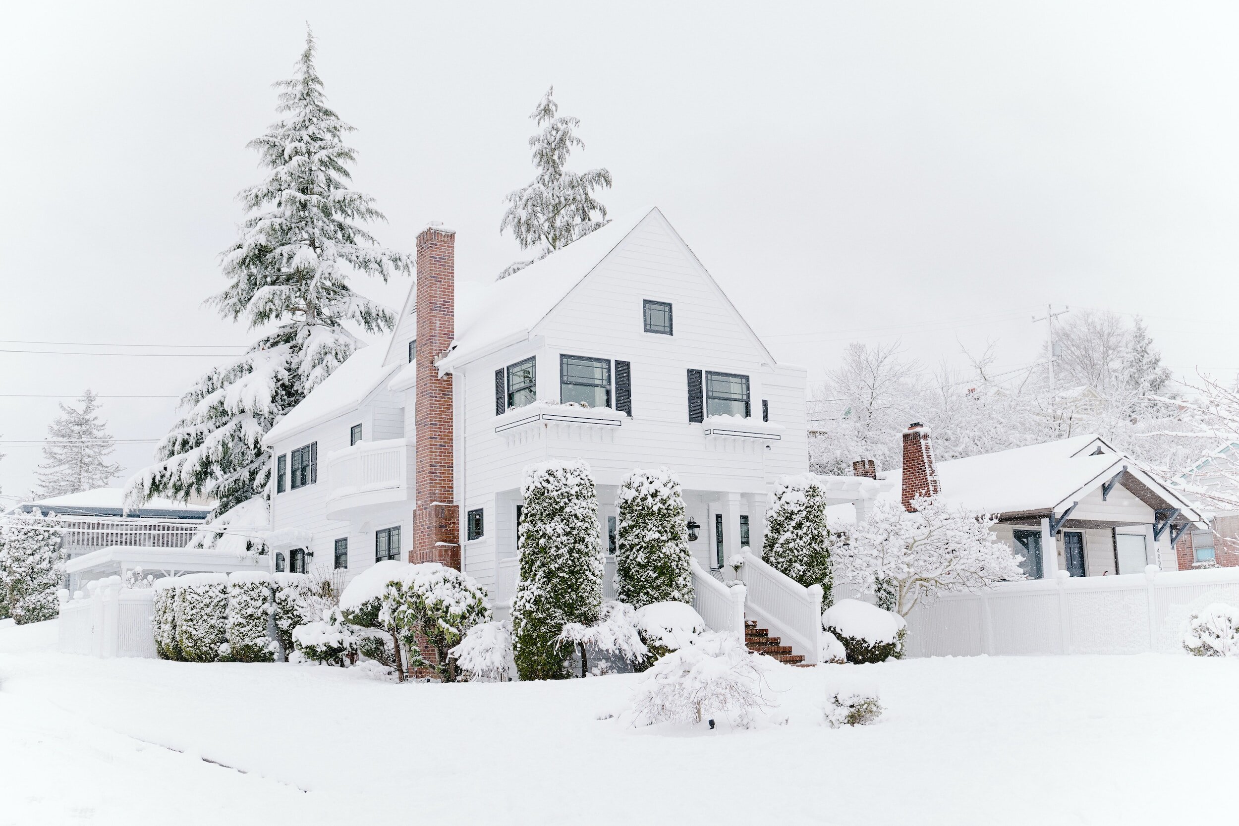 Charming white house surrounded by snow, offering a perfect winter retreat and an ideal property for sale